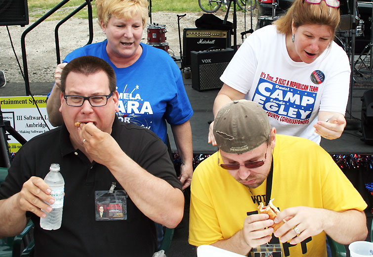 Republican District Attorney Candidate Gerald Benyo (left) and Republican Recorder of Deeds Candidate Tim Sempf entered the Nationality Days Hot Dog Eating Contest. They were cheered on by Republican Candidate for Prothonotary Pam Flara and Republican Commissioner Candidate Sandie Egley. Benyo came in second place having eaten 8 hotdogs in 5 minutes, just 1 behind the winner. / photo by John Paul Republican District Attorney Candidate Gerald Benyo (left) and Republican Recorder of Deeds Candidate Tim Sempf entered the Nationality Days Hot Dog Eating Contest. They were cheered on by Republican Candidate for Prothonotary Pam Flara and Republican Commissioner Candidate Sandie Egley. Benyo came in second place having eaten 8 hotdogs in 5 minutes, just 1 behind the winner. / photo by John Paul